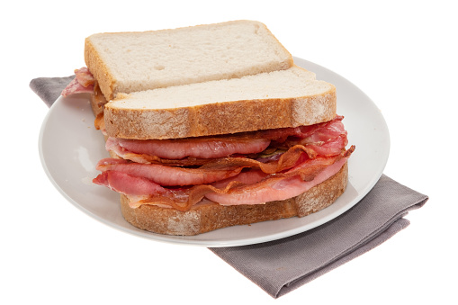 Two fresh submarine sandwiches with ham, cheese, bacon, tomatoes, lettuce, cucumbers and onions on dark wooden background