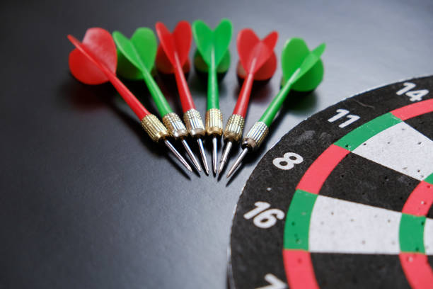 istock dartboard and red, green and yellow darts on a black background, 1291046048