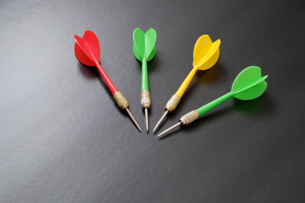 istock dartboard and red, green and yellow darts on a black background, 1291046899