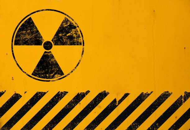 Black radioactive hazard warning sign painted over grunge yellow metal wall background with copy space