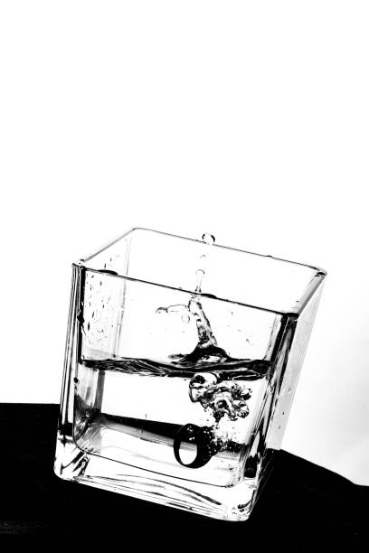 Ring into half-full waterglas Ringlike object falling into cubic Glas causing water splashes cuboidal epithelium stock pictures, royalty-free photos & images