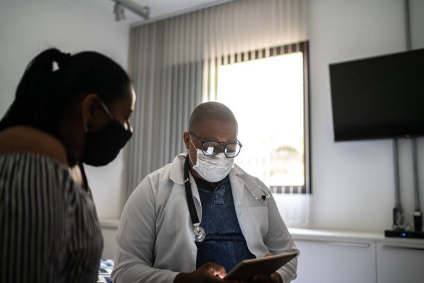 istock Doctor talking to a senior patient at home visit - using face mask 1291049314