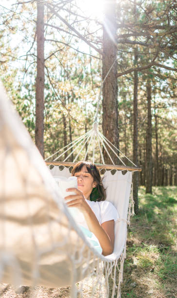 istock Women reading a book in forest hammock 1291050176