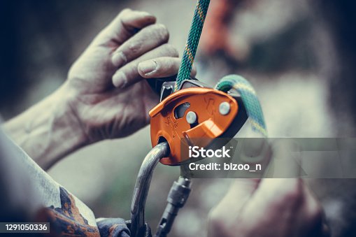 istock Man's hands operating a rock climbing belaying device 1291050336