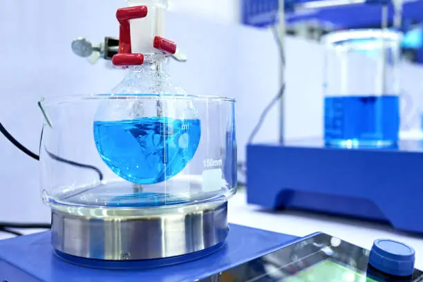 Close-up of stirring blue liquid at beaker in laboratory.