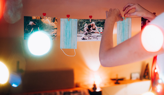 A collection of printed images of a embracing couple in love kissing, hanging on a clothesline,together with a protective face mask.
Concept photo