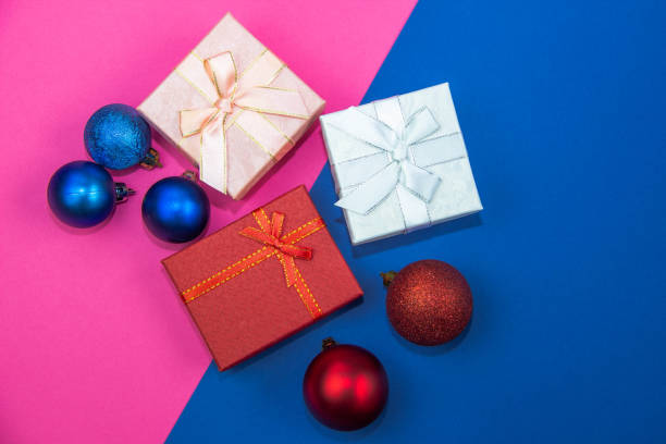 istock Christmas-tree decorations balls and gift boxes on a bright pink-blue background. Christmas and New Year's gifts. Flat lay, top view 1291052375