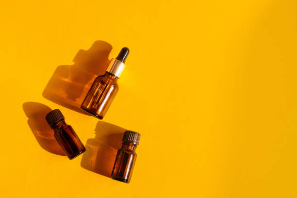 istock Glass cosmetic bottles on a bright sandy yellow background with hard shadows. Beauty blogger, procedures salon concept. Minimalism. Cosmetic dropper on a pink background. 1291052607