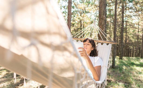 istock Women reading a book in forest hammock 1291053757
