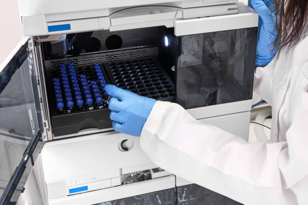 Scientist in a white lab coat putting vial with a sample into autosampler of HPLC system. High performance liquid chromatography at chemical laboratory. Developing of pharmaceuticals or vaccine. Biochemistry analysis. Scientist in a white lab coat putting vial with a sample into autosampler of HPLC system. High performance liquid chromatography at chemical laboratory. Developing of pharmaceuticals or vaccine. Biochemistry analysis chromatography stock pictures, royalty-free photos & images