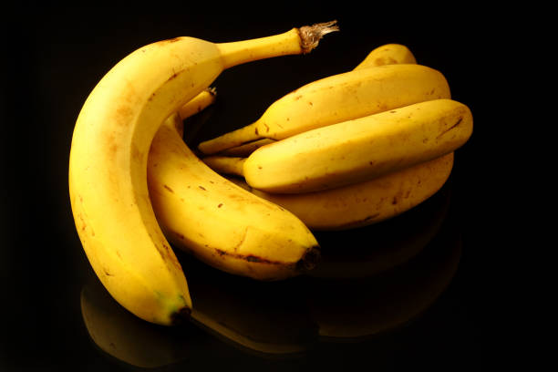 istock Bananas with some dark spots with shadow isolated on black background. 1291057846