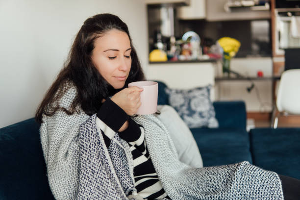 istock Sick woman suffering from cold drinking hot tea and trying to get warm 1291059317