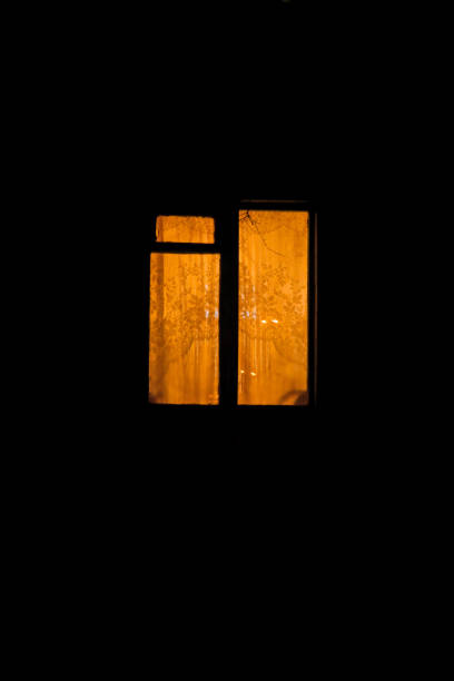 a window fogged up from below, glowing in the night with curtains of tulle and curtains