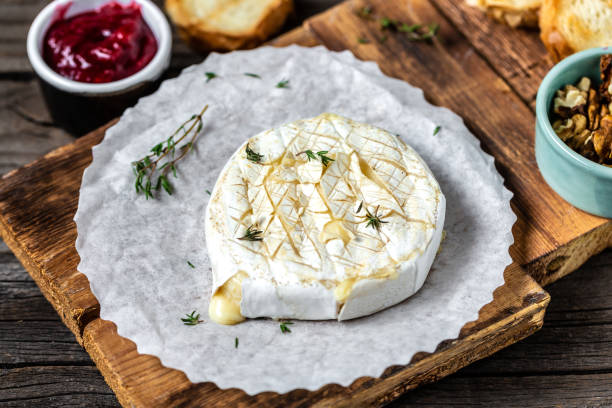 Baked Camembert cheese with toasted bread slices, thyme, cranberries and nuts. Traditional French cheese Baked Camembert cheese with toasted bread slices, thyme, cranberries and nuts. Traditional French cheese. brie stock pictures, royalty-free photos & images