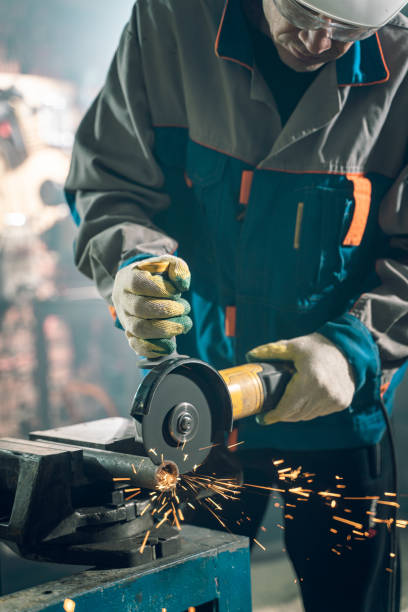 istock Locksmith in special clothes and goggles works in production. Metal processing with angle grinder. Sparks in metalworking 1291061323