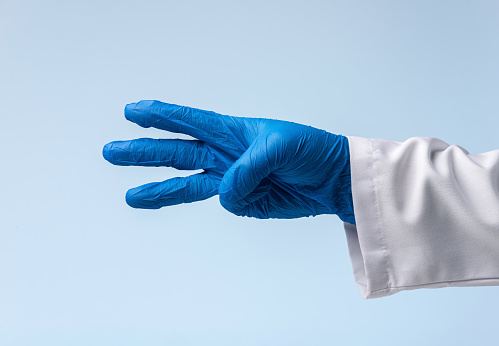 Doctor wearing blue rubber gloves is pointing with three fingers