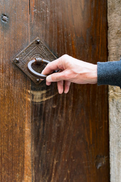 istock hand pulls on metal door knocker, on wooden door 1291062583