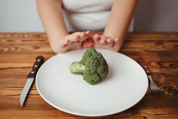 istock Overweight woman refusing small piece of vegetable 1291062960