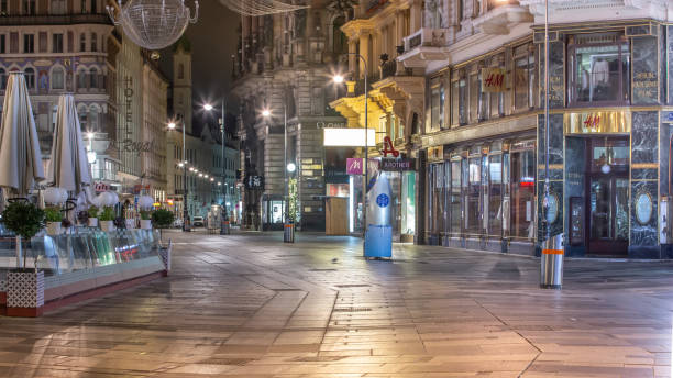 A closed H&M store in Vienna's first district during lockdown. VIENNA, AUSTRIA - DECEMBER 7, 2020 - The historical center has no visitors at night time of the second lockdown in 2020. During this period only pharmacies, banks, post offices, hospitals and supermarkets are allowed to stay open. Fashion stores have to remain closed and the city's Christmas decoration is switched off. There are no people around as the government asks everyone to remain at home between 20.00 and 06.00 therefore the usually busy areas are quiet. city street consumerism window display vienna stock pictures, royalty-free photos & images