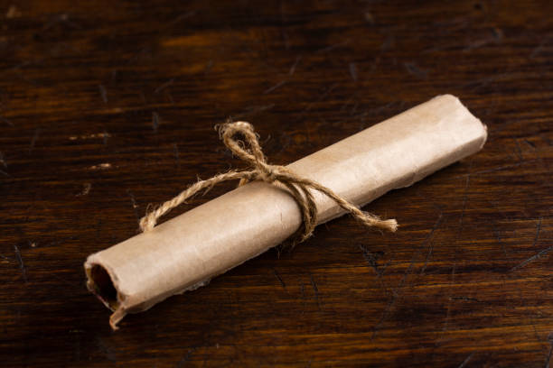 istock Old scroll tied with linen thread on an old wooden table. 1291065471