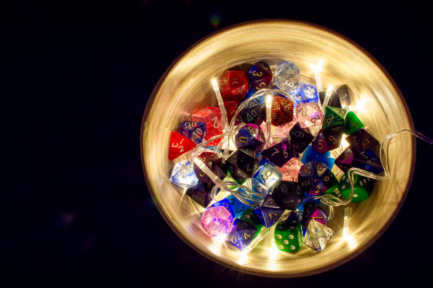 Bowl filled with dice A close-up of polyhedral dice of multiple colors in a bamboo bowl with Christmas lights developing 8 stock pictures, royalty-free photos & images