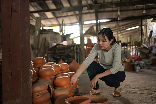 Young woman artist in ceramic workshop. Female potter examining pottery in studio. Professional Occupation