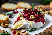 Baked Camembert brie with fresh rosemary and cranberry sauce. Gourmet appetizer. Breakfast, Food recipe background. Close up.