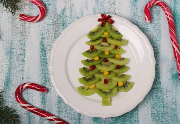 istock Christmas tree made from kiwi, corn and pomegranate, creative idea for Christmas and New Year festive dishes, fruit snack for children. Top view 1291070467