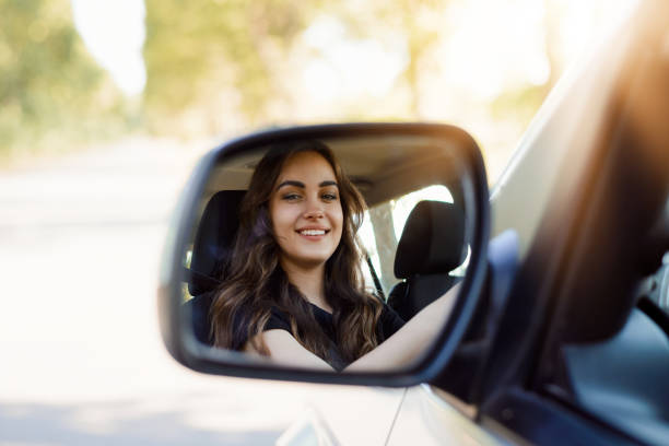 ●バックビューミラーを投げる新車の美しい若い女性の肖像画 - owner women car rear view mirror ストックフォトと画像