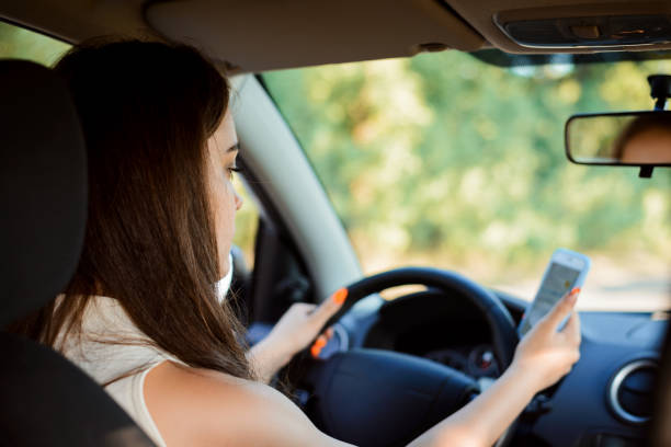 estudiante conductora conduciendo un coche y enviando mensajes de texto en el camino. - driving text messaging accident car fotografías e imágenes de stock