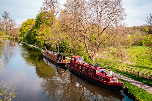 Narrow boats at river Gade, Grand Union Canal, on a sunny day. Cassiobury Park, Watford, Hertfordshire, England.