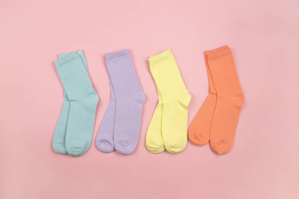 istock Colored children's socks without a pattern, pink, lilac, yellow, orange on a pink background with a place for text, copy space, flatly, minimal style. Concept for children's clothing, housekeeping 1291075262