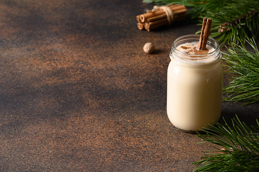 Holiday Christmas eggnog with cinnamon on brown background. Close up. Copy space.