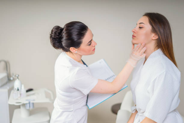 Professional cosmetician examining face skin of girl in clinic of esthetic cosmetology stock photo