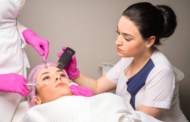 istock Two cosmetologists working with face of a patient at the same time 1291077495