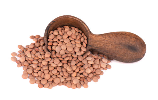 istock Brown lentils in wooden spoon, isolated on white background. 1291077616
