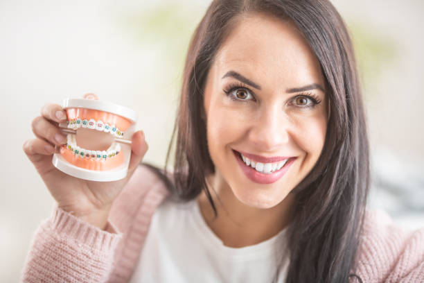 istock Smiling brunette holds a tooth porthesis with braces in her hand. 1291077972