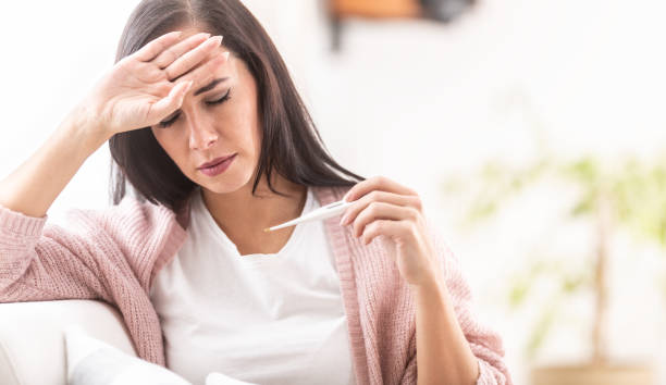 istock Fever having woman measures temperature with a standard thermometer. 1291078023