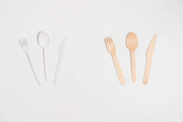 istock Disposable plastic spoon, fork and knife next to wooden cutlery on white background. Ecological vs. non-ecological. 1291079896
