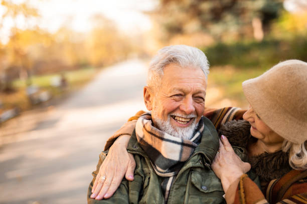 istock Romantic senior couple embracing while standing in the park on autumn day. 1291084853