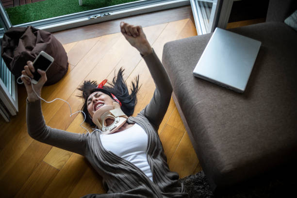 uma mulher com colarinho cirúrgico cervical realiza atividades em casa todos os dias - ela alegremente deita no chão, descansa, dança ouvindo música e se recupera com sucesso de uma lesão - human vertebra audio - fotografias e filmes do acervo