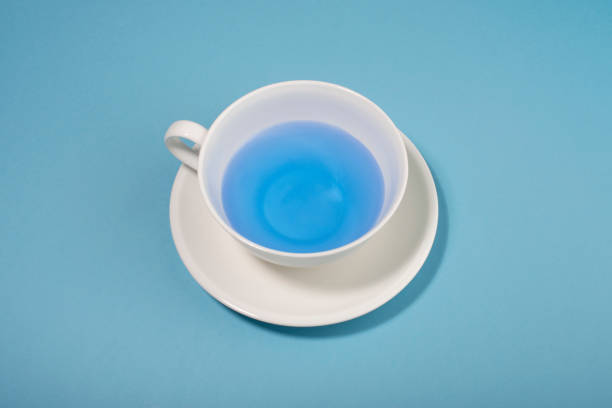 istock White cup with blue liquid on blue background. Blue Monday concept. 1291087193