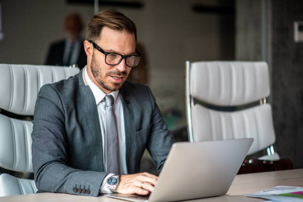 istock Young man sitting in conference room, using his laptop. 1291088538