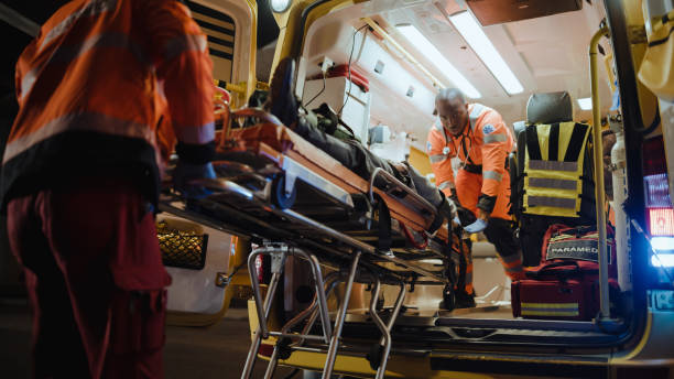 ems救急隊員のチームは、負傷した患者を医療病院に連れて行き、担架で救急車から彼を取り除くために迅速に反応します。救急医療アシスタントは、事故の後に生き続けるために若い男を助� - ambulance emergency services urgency healthcare and medicine ストックフォトと画像