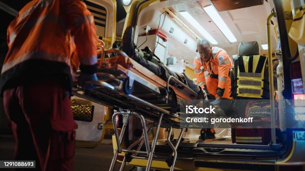 Team Of Ems Paramedics React Quick To Bring Injured Patient To Healthcare Hospital And Get Him Out Of Ambulance On A Stretcher Emergency Care Assistants Help Young Man To Stay Alive After Accident Stock Photo - Download Image Now