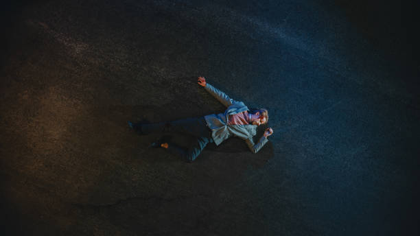 Top Down Shot of a Bloody Man Lying on the Pavement after Accident on a Street at Night. Young Man was Shot and Lies Unconscious. Concept of Horrbile Murder with Death. Top Down Shot of a Bloody Man Lying on the Pavement after Accident on a Street at Night. Young Man was Shot and Lies Unconscious. Concept of Horrbile Murder with Death. chalk outline stock pictures, royalty-free photos & images