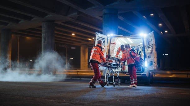 team of ems paramedics react quick to bring injured patient to healthcare hospital and get him out of ambulance on a stretcher. emergency care assistants help young man to stay alive after accident. - stretcher imagens e fotografias de stock