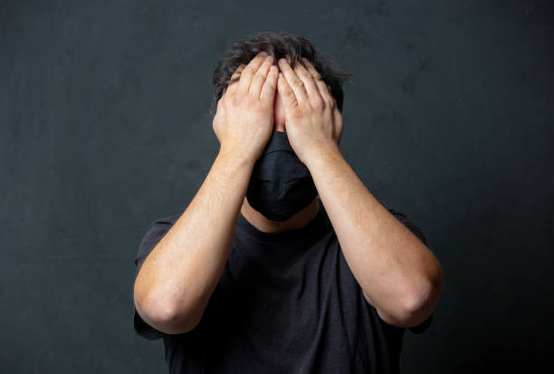 istock Tired brunet man in in black facemask on dark background 1291091933
