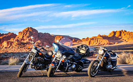 Three vintage motorcycles parked in front of the red rocks of Nevada's Valley of Fire.