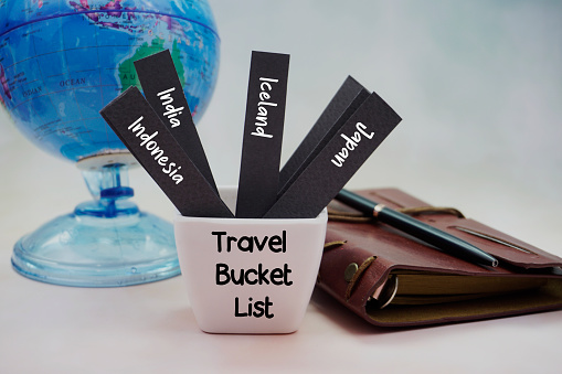 My Travel Bucket List written on paper. There are list of wishes written on papers and placed inside the bucket.